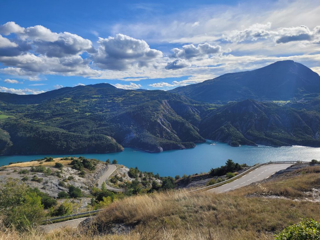 „Madártávlatból fotózott kanyargó hegyi út tóval és hegyekkel – a kiegyensúlyozott élet stratégiai térképének vizuális metaforája.